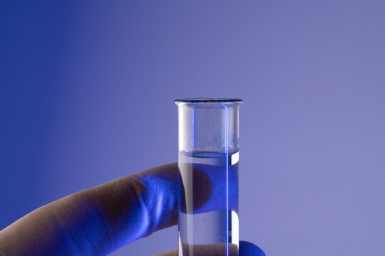 Chemist hand in glove holding test tube with blue liquid during longevity research in a modern science laboratory