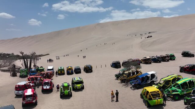 Aerial view of dune buggies gathered in desert landscape near Huacachina Oasis.