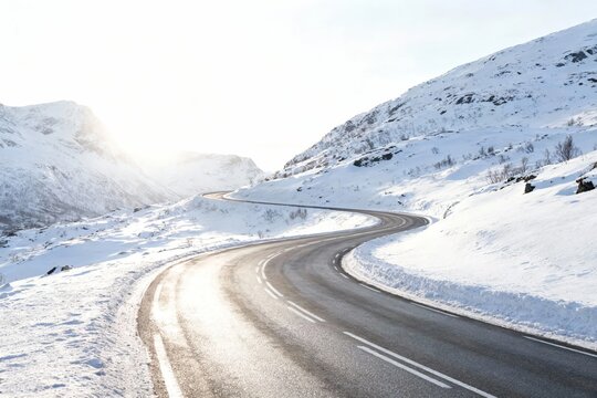 Snow-covered winding road through mountainous terrain on a bright winter day