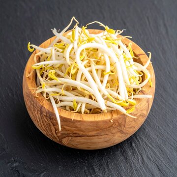 Fresh bean sprouts served in a rustic wooden bowl on a dark slate background for a healthy lifestyle and clean eating wellness concept theme.