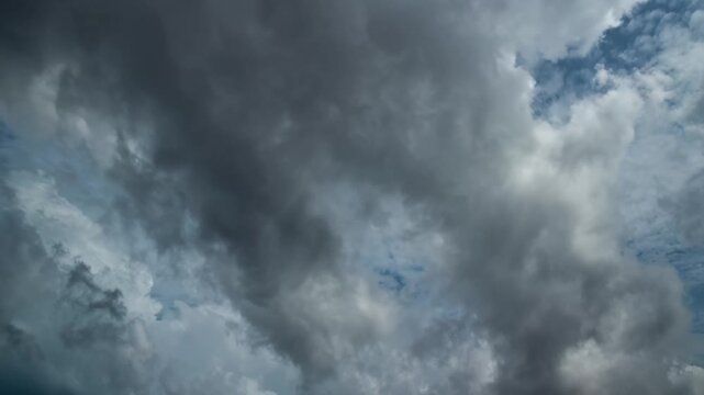 Time-lapse of dramatic storm clouds forming and moving across the sky, with patches of blue breaking through