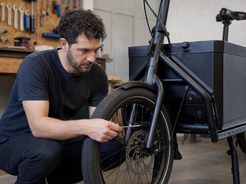 Mechanic inspecting brakes on an electric cargo bicycle