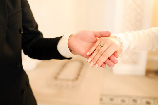 Bride&rsquo;s hand with wedding and engagement rings resting in the groom&rsquo;s hand after a Muslim nikah ceremony. Romantic Islamic wedding detail representing marriage, love, commitment and newlywed life.
