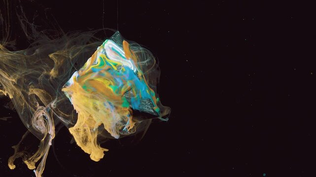 Colorful triangular fluid mass detaching with translucent tendrils against black background, frontal closeup with pearlescent