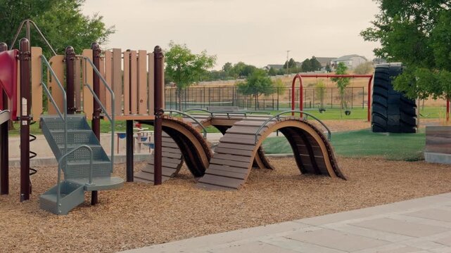 Static view of empty playground equipment as cars pass along a distant street