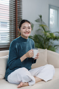 Asian woman enjoying warm coffee at home