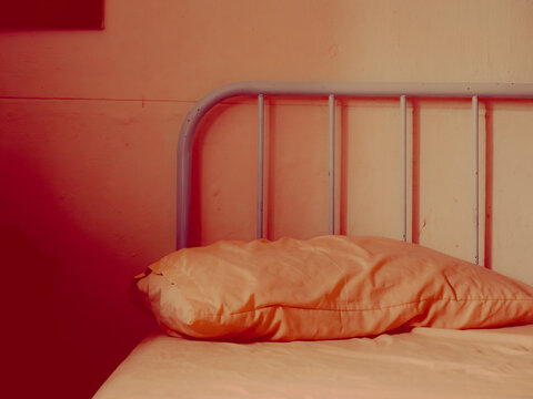 Moody Red-Toned Bedroom Scene with Orange Pillow and Metal Headboard, Minimal Interior