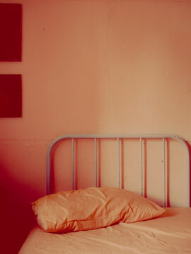Moody Red-Toned Bedroom Scene with Orange Pillow and Metal Headboard, Minimal Interior