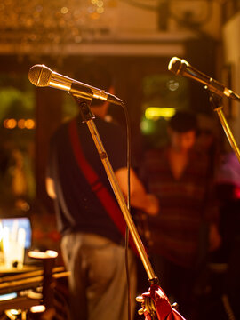Microphone on Stand at Live Music Venue with Blurred Band in Background
