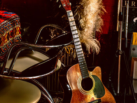Vintage Acoustic Guitar Neck Leaning Against Chrome Chairs in Moody Music Room