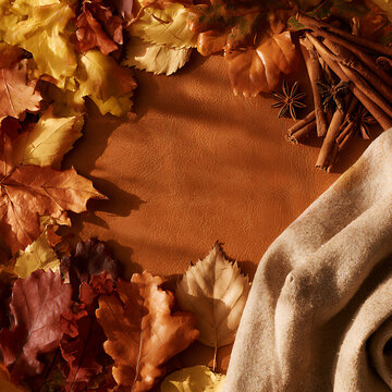 Fall leaves and spices on a brown background with a cozy cloth in a warm setting