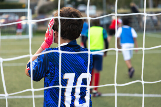 rear view of teenage goalie defending soccer net in game