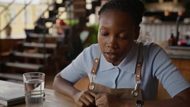 Young adult African American barista discussing schedule on clipboard with manager in coffee shop. Footage ideal for hospitality training, small business management, and staff onboarding