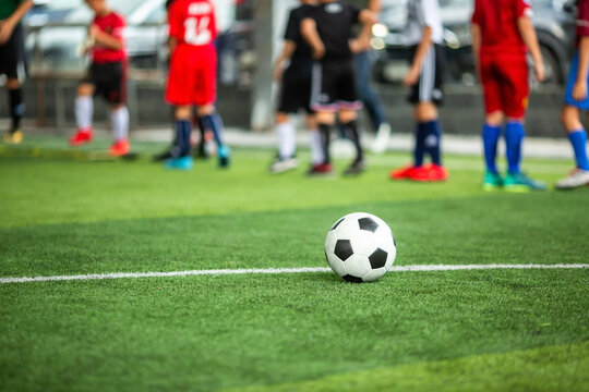 Soccer Ball on Artificial Green Turf Field with Blurred Players Background