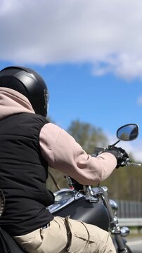 Experience the exhilaration of freedom as a motorcyclist rides along an open asphalt road. The headwind whips through their hair, capturing the essence of adventure and speed