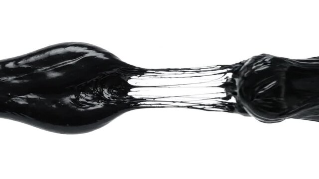 Black viscous substance stretching and snapping back on white background