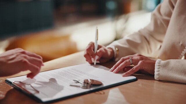 Keys, shaking hands and signature in home with document, lease contract and form for administration. People, legal paperwork or rental agreement with handshake in house for policy, mortgage or loan