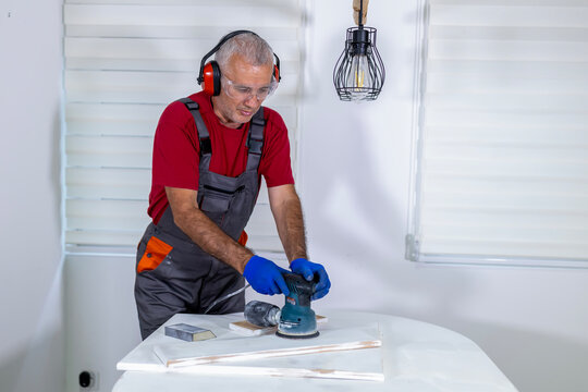 Carpenter sanding wood with orbital sander for restoration project