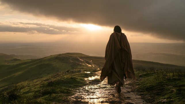 A lone figure in a robe walking along a muddy path on a hillside at sunset
