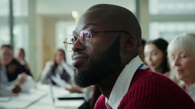 A professional man smiles and listens attentively in a business meeting. Focus and engagement in a corporate setting, highlighting learning and collaboration among colleagues at a conference.