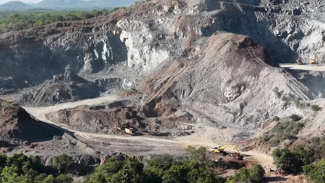 Excavators and trucks working to extract stones from a large deep open pit mine in South Kalimantan