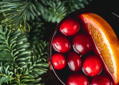 Mulled wine with orange, cranberry and cinnamon in fir forest setting. Selective focus.