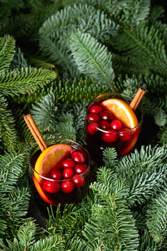 Mulled wine with orange, cranberry and cinnamon in fir forest setting. Selective focus.
