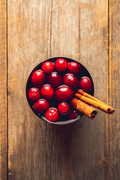 Mulled wine with orange, cranberry and cinnamon on rustic wooden background. Selective focus.