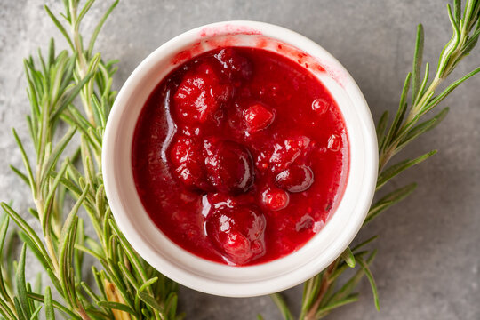 Homemade cranberry sauce in white ceramic bowl on concrete background