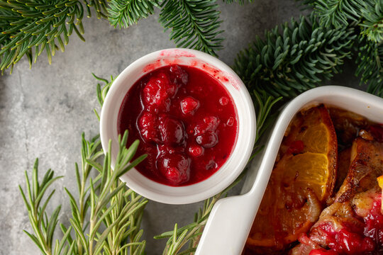 Homemade cranberry sauce in white ceramic bowl on concrete background