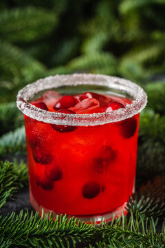 Red christmas cocktail with cranberry juice on the fir branches background. Christmas mood. Selective focus. 