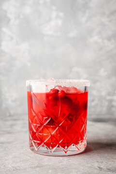 Red christmas cocktail with cranberry juice on the gray concrete background. Christmas mood. Selective focus. 