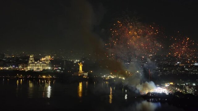 Wide view of Heavy smoke on Grand Sataabdi Utsav in People's Plaza with fireworks, water reflections and illuminated city at hyderabad, telangana, india. night time, trucking shot, drone shot, 4k.