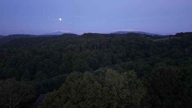 aerial push toward grandfather mountain in north carolina with the moon overhead