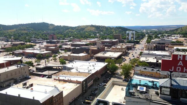Aerial drone flying past the Hotel Alex Johnson sign revealing more of downtown Rapid City, South Dakota