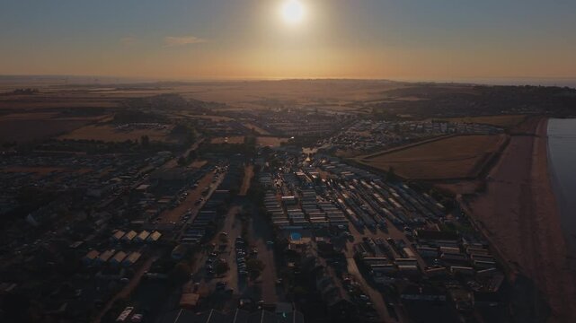 Aerial view, Leysdown-on-Sea on the Isle of Sheppey, Kent, after the partial solar eclipse, with residential streets and coastline in warm evening light