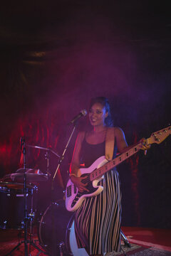 Musician playing electric guitar on stage, enjoying live performance with band, copy space
