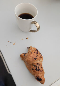 Coffee and chocolate croissant on a table during morning time in a casual setting