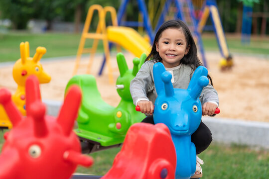 happy preschool child girl playing and riding carousel at playground