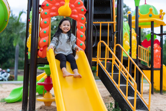 preschool child girl sliding down a playground slider.