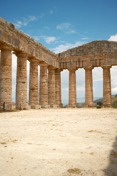 Vertical low-angle interior view of Doric colonnade and corner pediment under blue sky in Segesta, Sicily, Italy