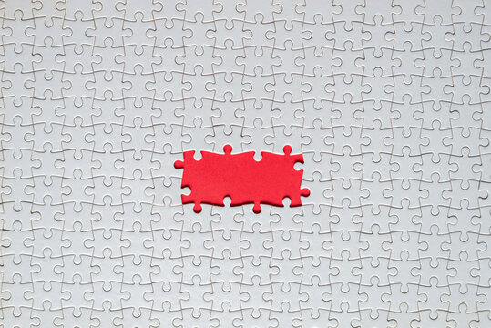White jigsaw puzzle with missing pieces revealing red background