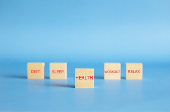 Wooden block with Health text in focus and blurred wellness keywords on blue background