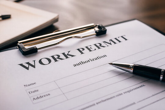 A close-up of a work permit form with a pen resting on it.
