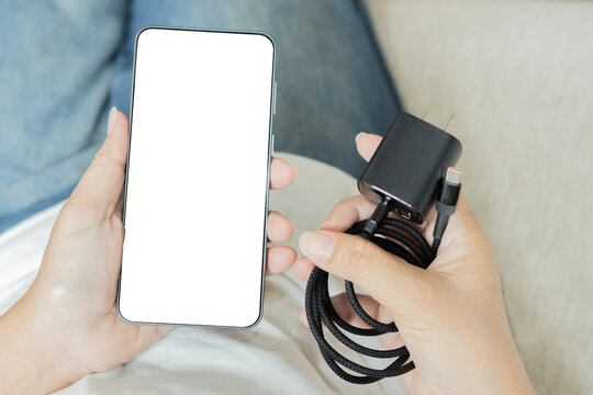 A top view of a person holding a modern smartphone with a blank white screen
