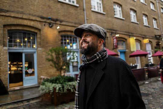 Smiling man with beard and flat cap walks in a winter city market