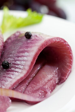 Herring in sherry vinegar with onions on plate, close up