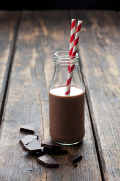 Glass bottle of cocoa and bittersweet chocolate on wood