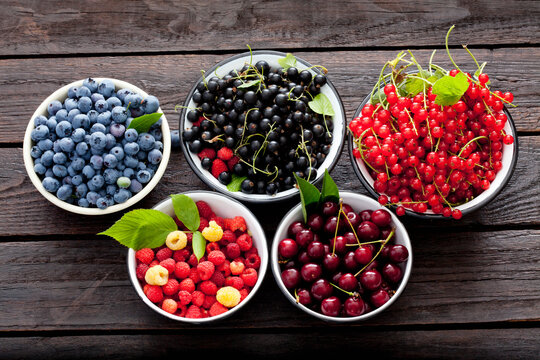Bowls of sour cherries, raspberries, red and black currants and blueberries
