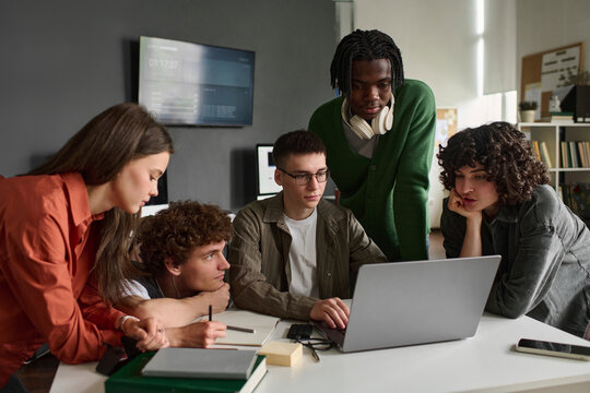 A student group looks at a laptop in the university classroom